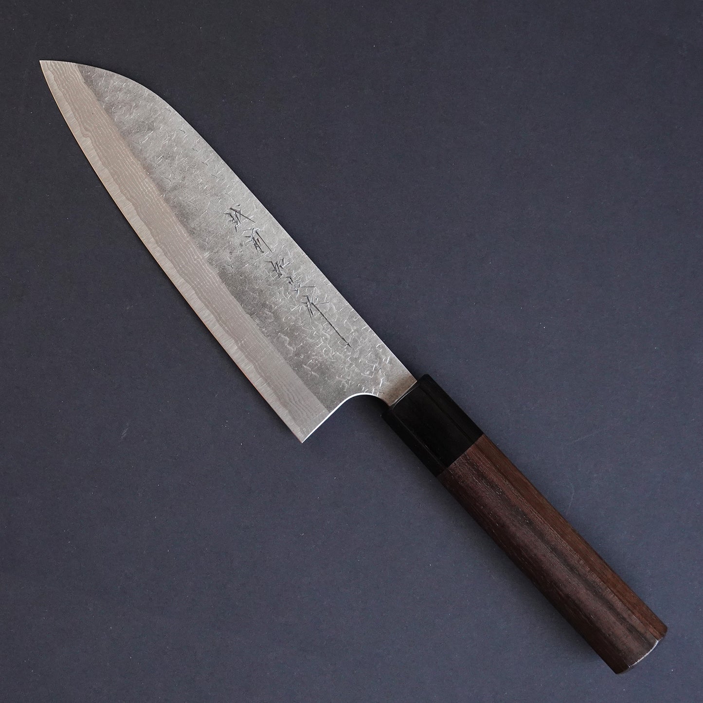 Cuchillo japonés de estilo tradicional con hoja de Damasco martillada con el nombre del fabricante grabado en él.