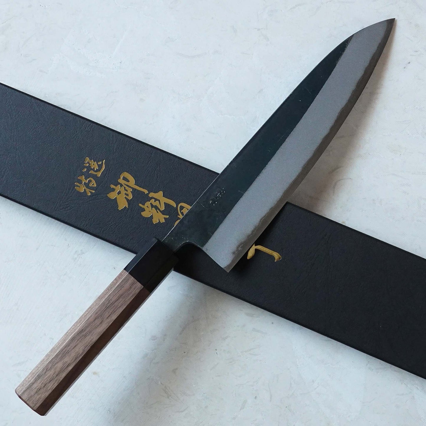 Cuchillo japonés Gyuto forjado en negro de estilo tradicional, con caja de presentación.
